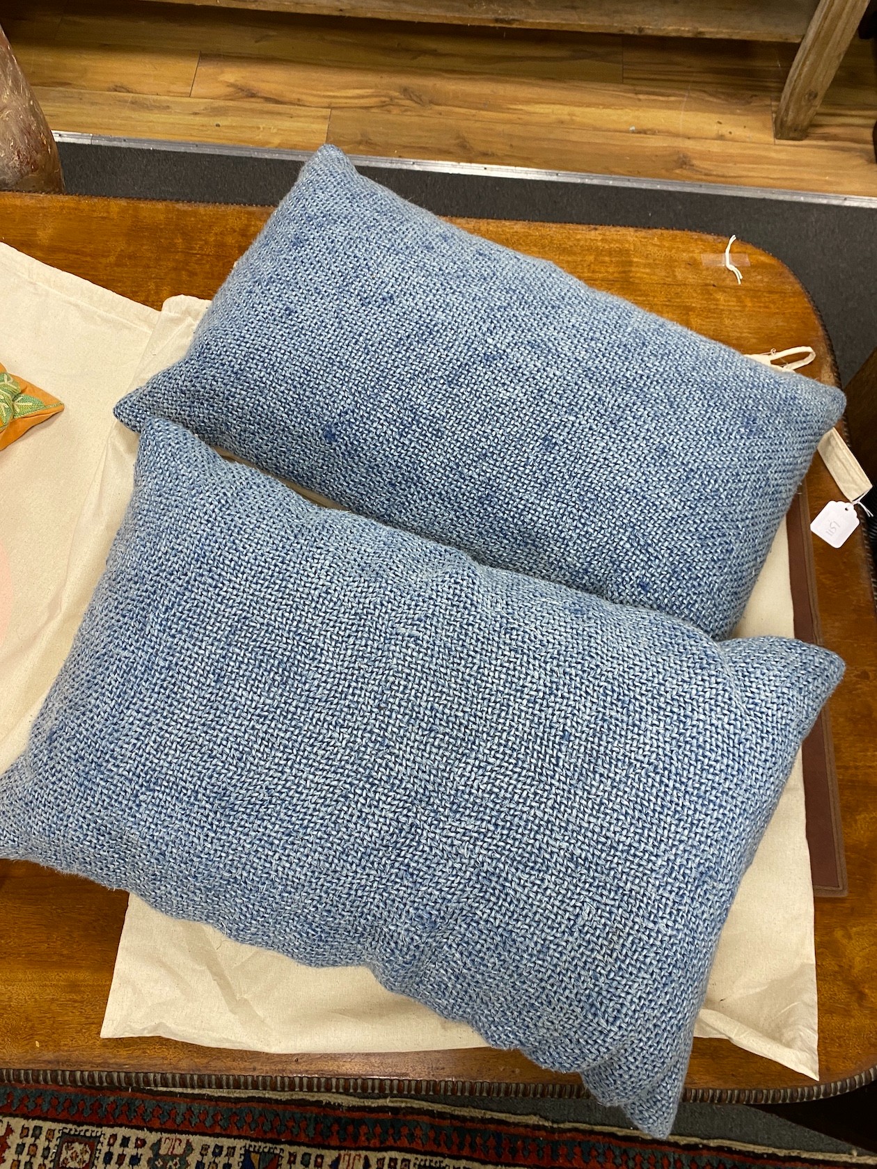 Two pairs of polychrome floral embroidered and blue woven cushions, larger 50cm square.